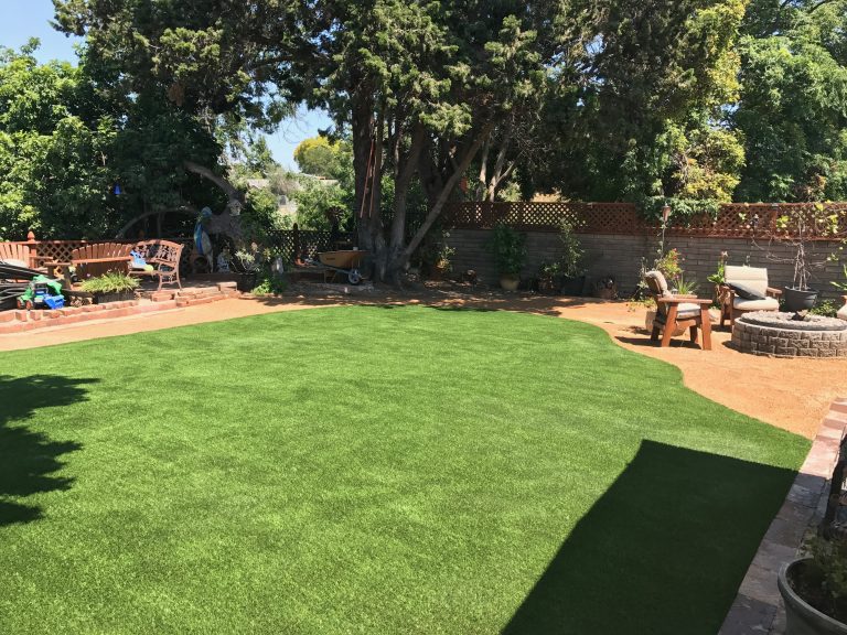 Backyard artificial lawn shaded by mature trees