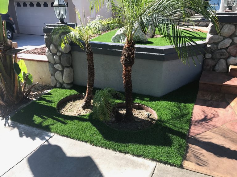 Synthetic turf around a palm tree and stone planter