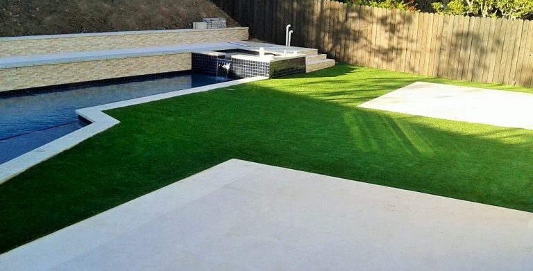 Artificial grass lawn beside a backyard pool and spa