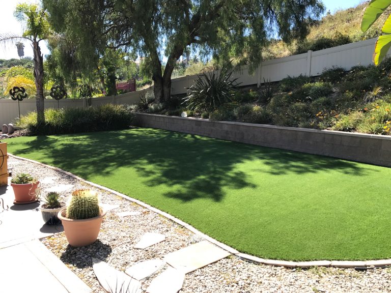 Backyard artificial lawn below a landscaped hillside