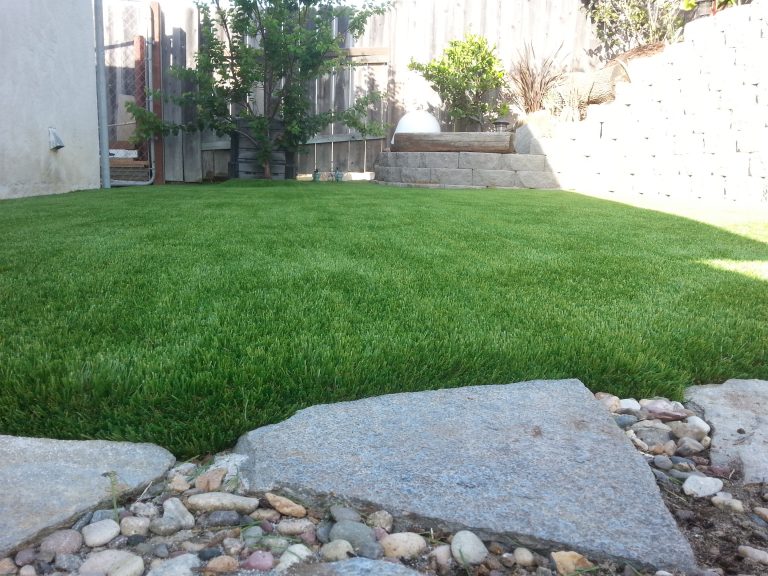 Artificial lawn framed by river rock and boulders