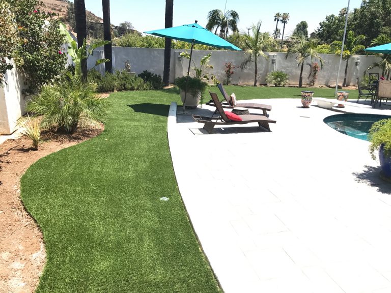 Artificial grass border beside a pool deck with lounge chairs
